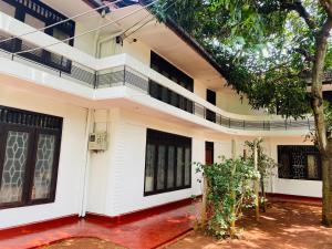 una casa con paredes blancas y un árbol en Nallur Residence, en Jaffna