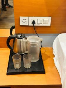 a tea kettle and three glasses on a tray on a table at Flora hotel in Jodhpur