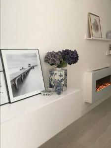 Cette chambre blanche dispose d'une cheminée et d'un vase avec des fleurs. dans l'établissement Moderno apartamento con garaje privado en el centro de Vigo, à Vigo
