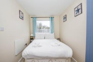 een slaapkamer met een wit bed en een raam bij Seaside Retreat Norfolk in Bacton