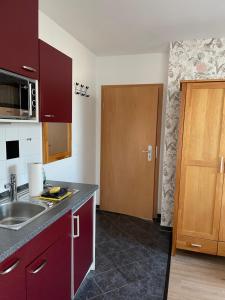uma cozinha com armários vermelhos, um lavatório e uma porta em Ferienhaus Kaptein Meyer em Zingst