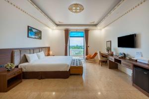 a hotel room with a bed and a desk and a television at Trang An International Hotel in Ninh Binh