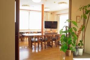 comedor con mesa, sillas y TV en TESHIKAGA HOSTEL MISATO en Teshikaga