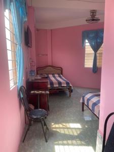 a room with two beds and a desk and a chair at Huỳnh Hương Guesthouse in Hà Tiên