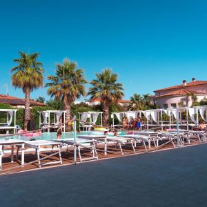 a pool with chaise lounge chairs and palm trees at Principi di Piemonte con Piscina in Tirrenia