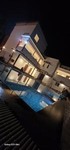 un edificio iluminado con piscina por la noche en LGR Club House en Poringalkuthu