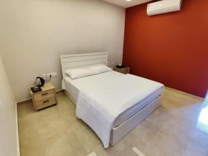 1 dormitorio con cama blanca y pared roja en LGR Club House en Poringalkuthu