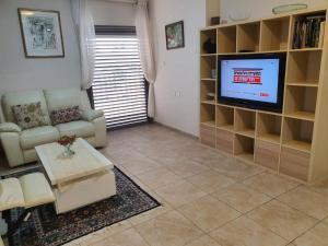 a living room with a couch and a tv at Lovely Apartment with shalter room in Tel Aviv