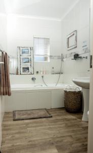 un bagno bianco con vasca e lavandino di Nine on Uys street B & B a Jeffreys Bay
