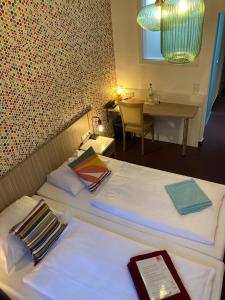 Cette chambre d'hôtel comprend 2 lits avec une table et une table. dans l'établissement Hotel Madeleine Biohotel, à Sarrebruck