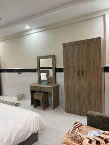 a bedroom with a bed and a vanity and a mirror at سحاب الأندلس للأجنحة الفندقية - املج in Umm Lajj