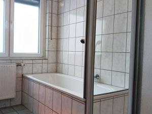 a bath tub in a tiled bathroom with a window at Abendsonne Obergeschoss mit Balkon in Koblenz