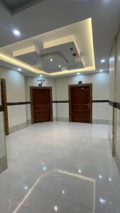 a large empty room with two wooden doors at سحاب الأندلس للأجنحة الفندقية - املج in Umm Lujj