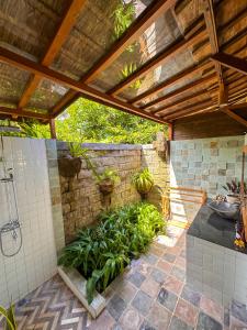 a bathroom with a shower and a stone wall at Nunu Bali Eco Friendly Retreat in Canggu