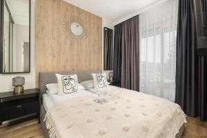 a bedroom with a white bed with a mirror at Beach Apartments Perłowa Przystań Sztormowa by Renters in Sianozety