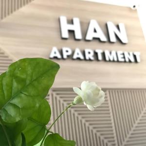 una flor blanca delante de un signo de nombramiento de hombre en Han Apartment en Da Nang