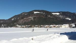 dos personas esquiando en la nieve frente a una montaña en Ferienwohnung Gilch, en Oberwössen