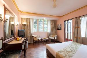 a hotel room with a bed and a desk and a television at Nahar Heritage Hotel in Bengaluru