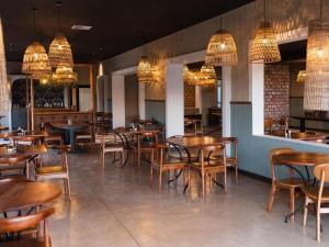 a restaurant with wooden tables and chairs and chandeliers at Lodge Damaraland in Khorixas