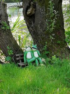 a toy frog sitting on a bench next to a tree at Am Froschteich in Dolgen