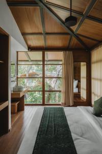 a bedroom with a bed and a large window at Grün Resort Uluwatu in Uluwatu