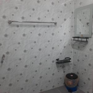 a white tiled bathroom with a toilet and a mirror at Hidden Homestay in Marang