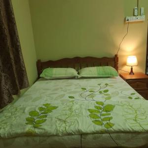a bed with a green comforter and two pillows at Hidden Homestay in Marang