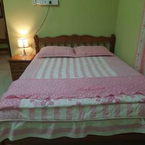 a bed with pink and white sheets and a lamp at Hidden Homestay in Marang