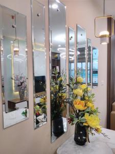 un groupe de miroirs sur un mur avec des fleurs dans un vase dans l'établissement Bach Dang Apartment Hai Duong, à Hải Dương