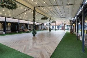 a pavilion with a wooden floor and lights at OYO Tudor Oaks Lodge Stevenage North in Astwick