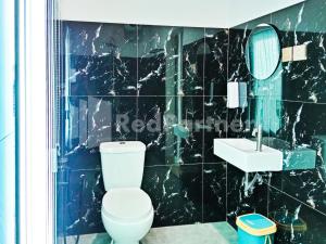 ein schwarz gefliestes Badezimmer mit Toilette und Waschbecken in der Unterkunft Cerry Village near RS Mitra Siaga Tegal RedPartner in Tegal + 14 Fotos
