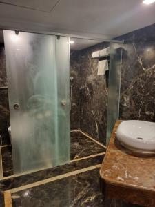 y baño con lavabo y ducha acristalada. en Hotel Benzz Park Chennai en Chennai