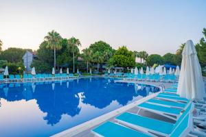 a swimming pool with lounge chairs and umbrellas at Master Family Club in Manavgat