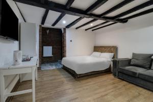 a bedroom with a bed and a couch at OYO Tudor Oaks Lodge Stevenage North in Astwick