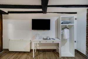 einen weißen Schreibtisch mit einem TV an der Wand in der Unterkunft OYO Tudor Oaks Lodge Stevenage North in Astwick