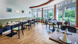 a dining room with tables and chairs and windows at Landhotel Zur Eiche in Buxtehude +32 photos