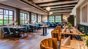 ein Restaurant mit Tischen, Stühlen und Fenstern in der Unterkunft Landhotel Zur Eiche in Buxtehude