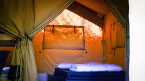 a bed in a tent with two white pillows at Safari Tent XL Camping Belle-Vue in Berdorf