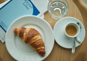 einen Teller mit einem Croissant und einer Tasse Kaffee in der Unterkunft kleiner Löwe – Stadthotel Bregenz in Bregenz
