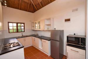 cocina con armarios blancos y nevera de acero inoxidable en The Little Outlook en Victoria Falls