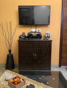 a television on top of a cabinet with a box of fruit at Aquila Home 2 BHK South Delhi Near Ashram Metro in New Delhi