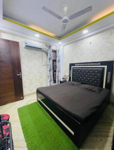 a bedroom with a black bed and a green rug at Aquila Home 2 BHK South Delhi Near Ashram Metro in New Delhi