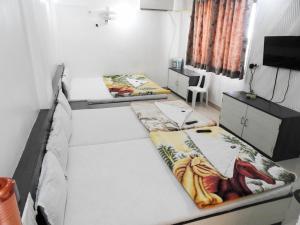 a room with two beds and a tv in it at Hotel Shri Sai Darshan in Shirdi