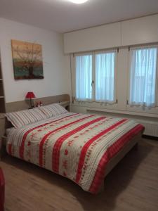 a bedroom with a bed with a red and white blanket at Casetta gialla in Pieve di Cadore