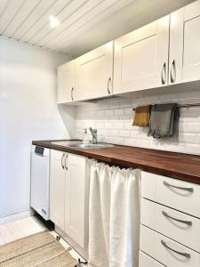 uma cozinha com armários brancos e um lavatório em Cute loft by Tram Stop em Helsinque