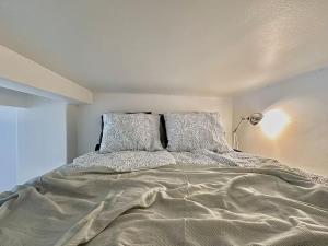 a white bedroom with a bed with two pillows at Cute loft by Tram Stop in Helsinki