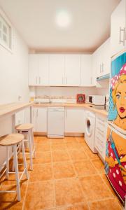 cocina con armarios blancos y suelo de baldosa naranja en PRECIOSO DúPLEX PLAZA NUEVA, en Granada