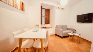 Un comedor con una mesa y sillas blancas. en PRECIOSO DúPLEX PLAZA NUEVA, en Granada