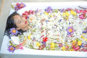 a woman laying in a bath tub filled with flowers at Rockery Villa Ayurveda in Bentota