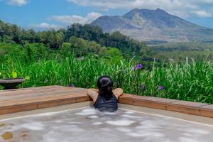 a woman sitting in a hot tub looking at a mountain at Calidas Hill in Kintamani